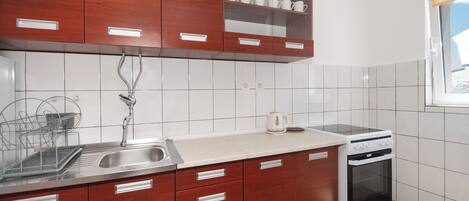 A kitchen with wooden cabinets, a stainless steel sink, a white countertop, and a built-in oven.