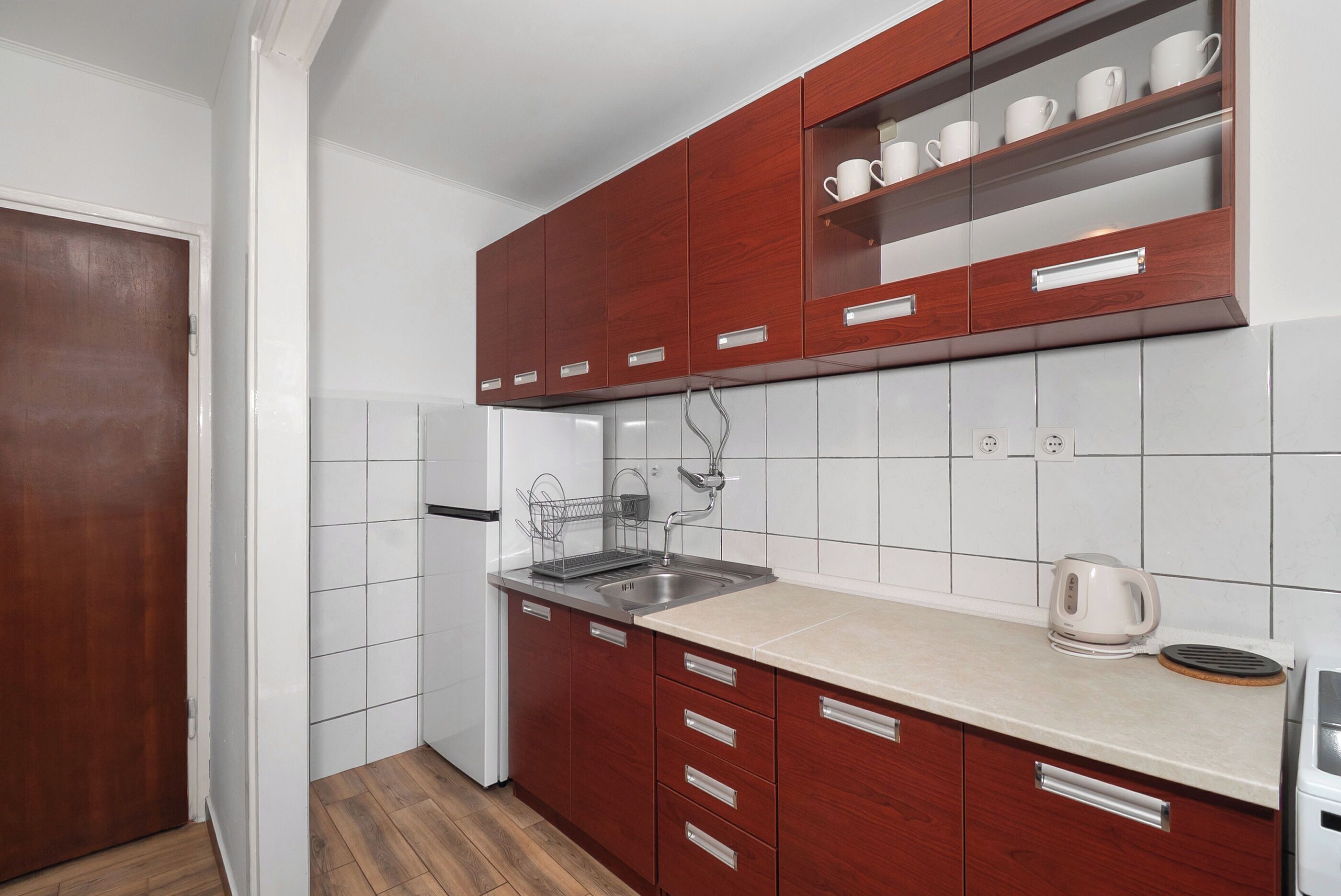 A kitchen with wooden cabinets, a stainless steel sink, and a white countertop.