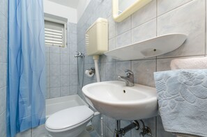 A bathroom with a toilet, sink, and shower curtain. - Apartment Damir (Primosten)