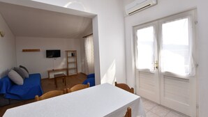 A room with a bed, a table, chairs, a TV, and a window with curtains. - Apartment Damir (Primosten)
