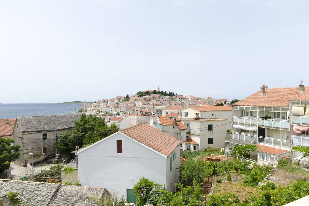 Eine Küstenstadt mit Häusern, einer markanten Struktur auf einem Hügel und Blick aufs Meer.