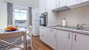 A modern kitchen with white cabinets, a built-in oven, and a sink. - Apartments Vladimir (Primosten)
