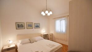 Siististi järjestetty makuuhuone, jossa on sänky, yöpöydät ja riippuvalaisin.