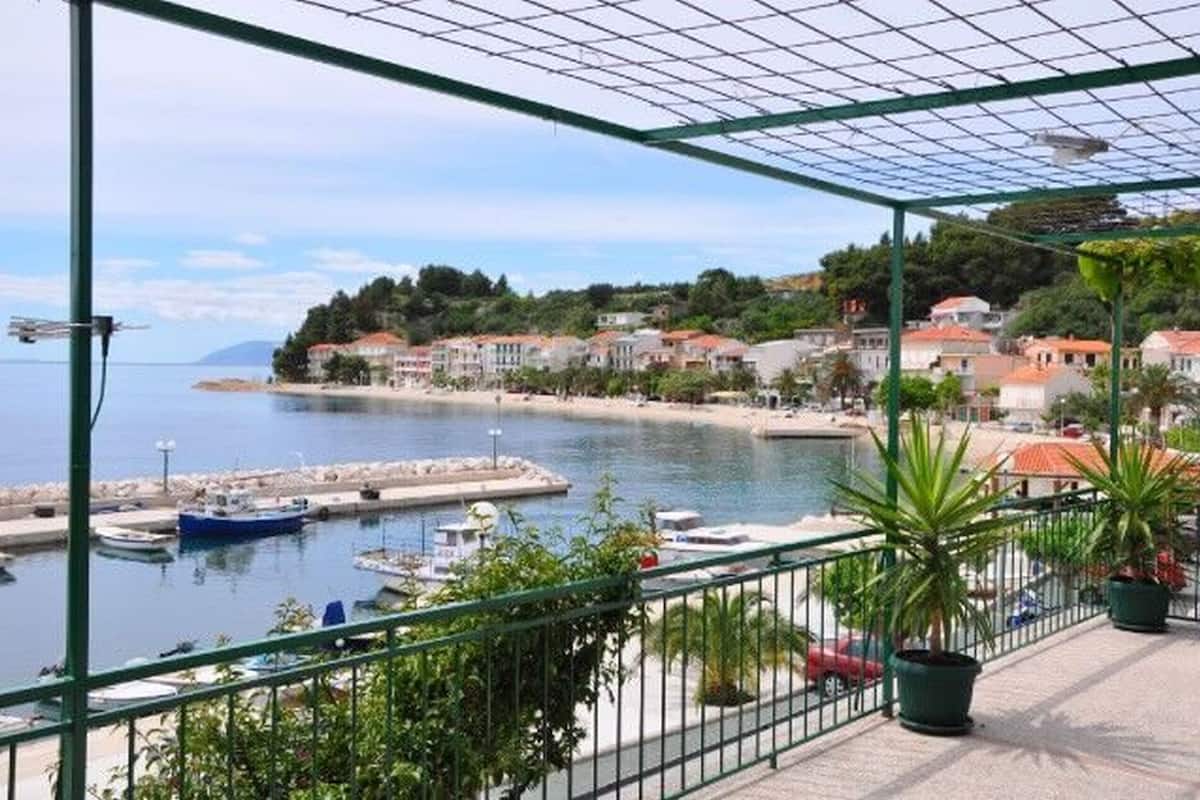 A balcony with a view of a marina, boats, and a coastal town.