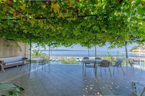 Une terrasse extérieure avec vue sur la mer, un espace salon et une table avec des chaises.