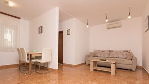 A living room with a sofa, dining table, chairs, and a coffee table. - Apartments Frane (Primosten)