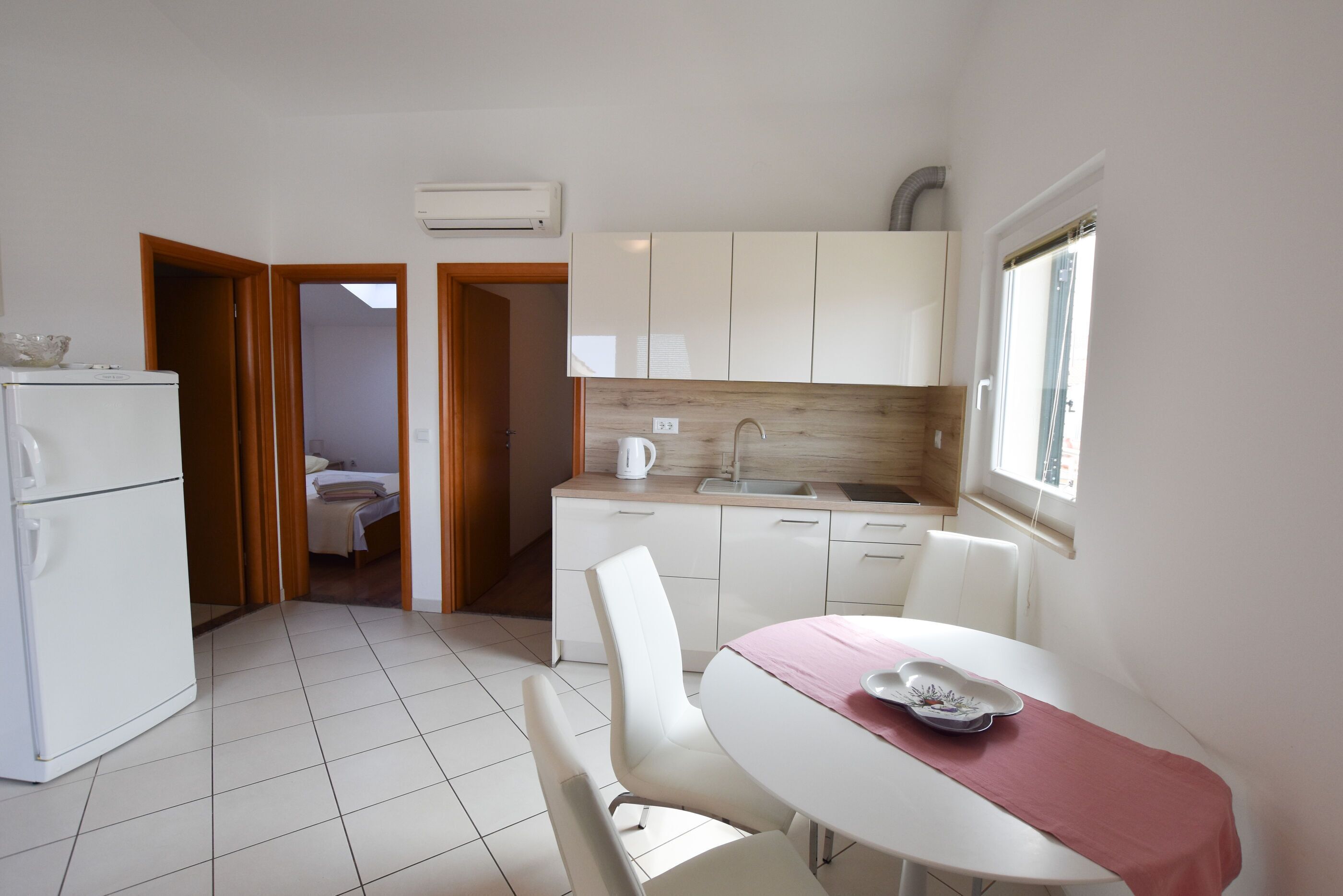 A compact kitchen with white cabinets, a sink, and a window.