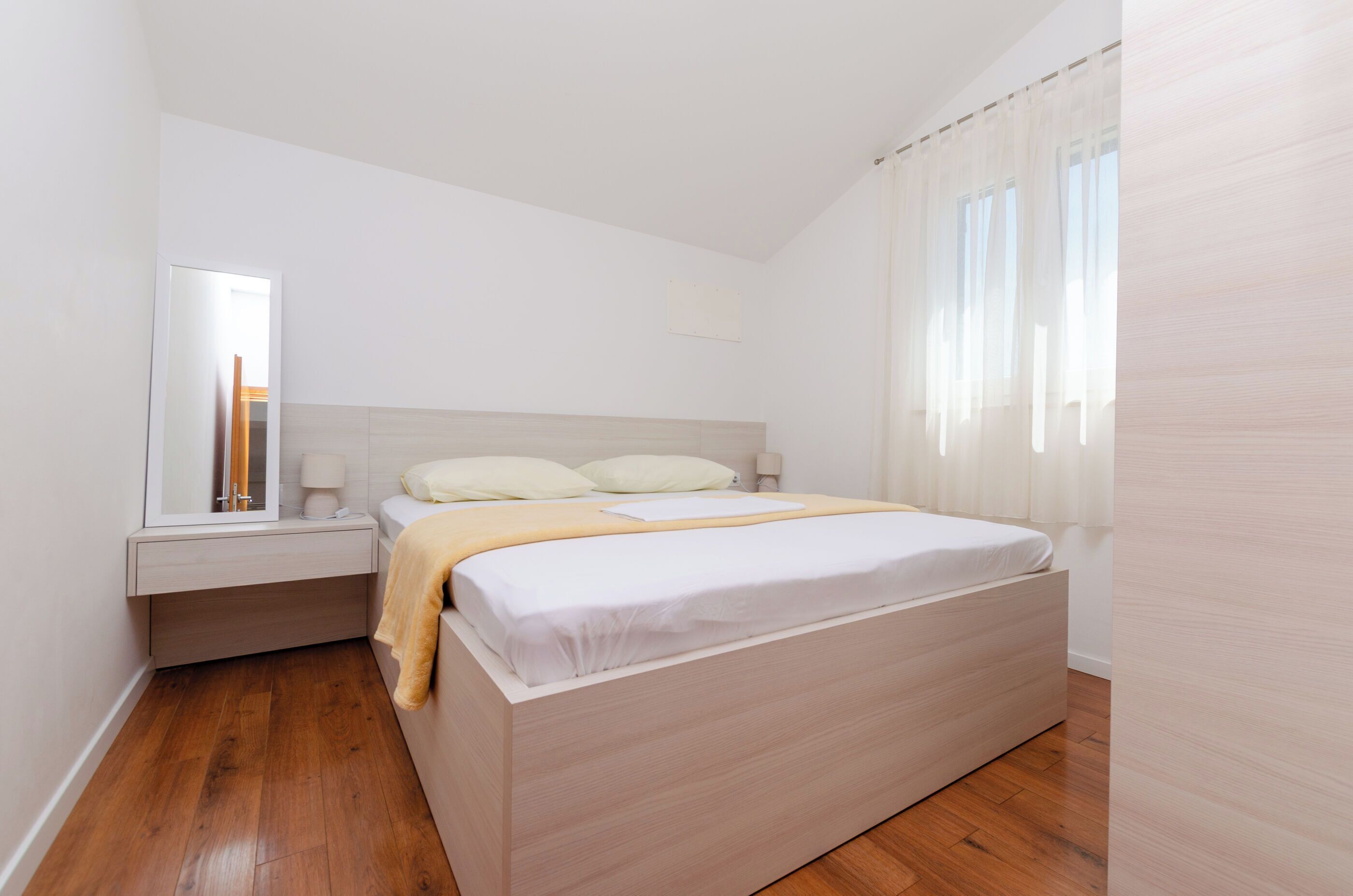 Un dormitorio con cama, mesita de noche y espejo.