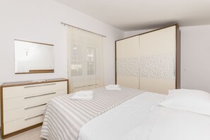 A bedroom with a bed, a dresser, a mirror, and a wardrobe. - Apartments Maja (Okrug Gornji)