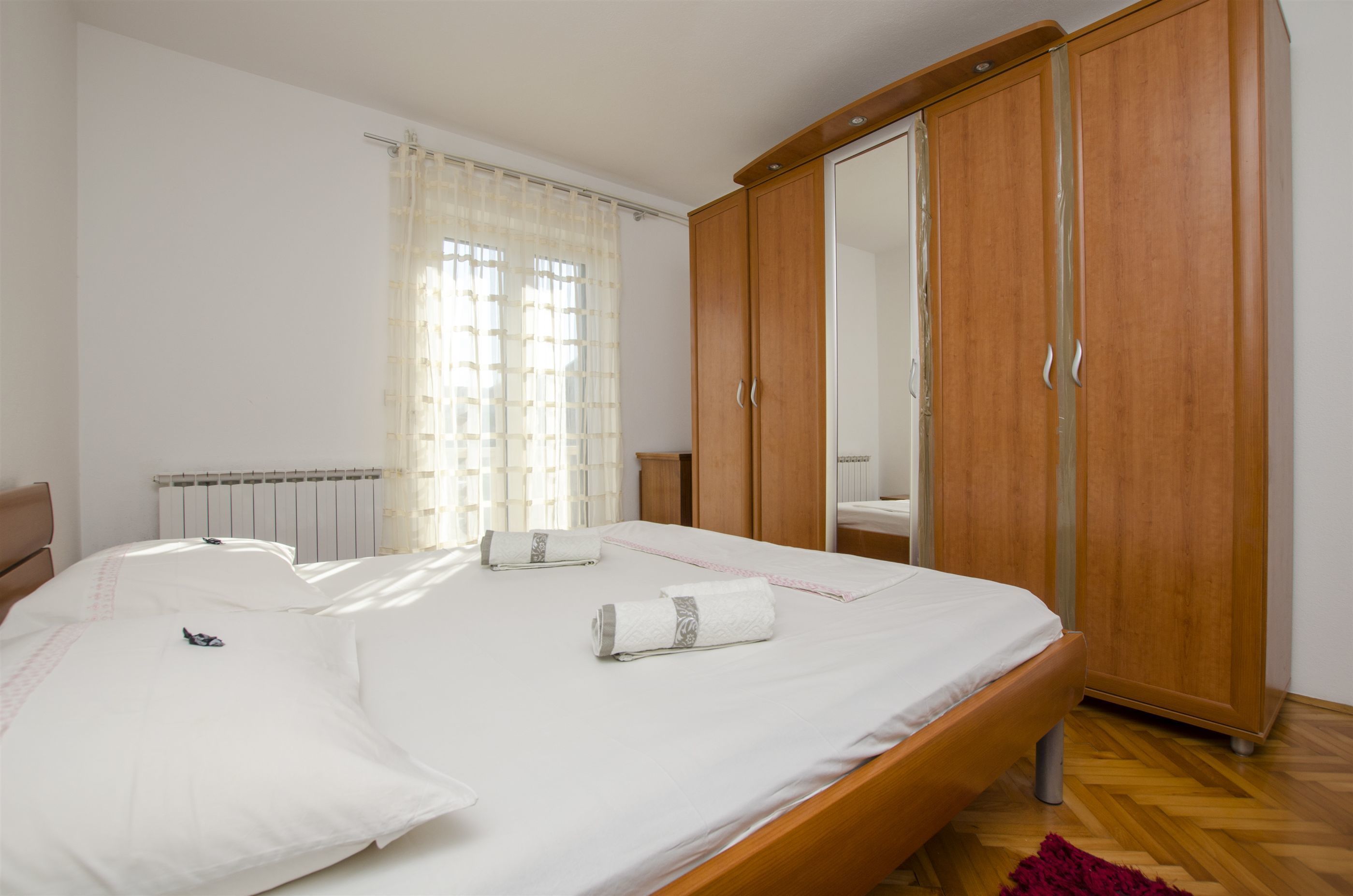 A bedroom with a wooden bed, a wardrobe, and a radiator.