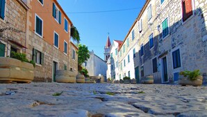 A cobblestone street lined with historic buildings, some with potted plants on the ground. - Apartments Mare (Postira)