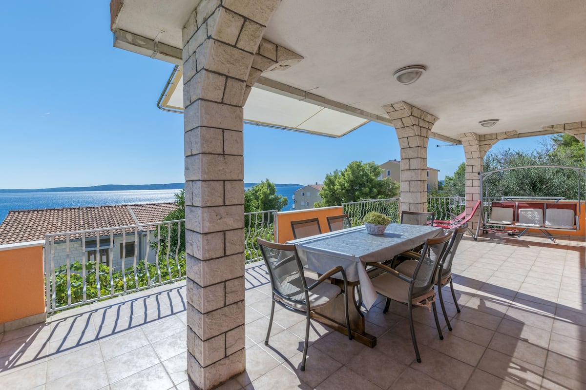Ein Balkon mit Tisch und Stühlen, der einen schönen Ausblick auf das Meer und die Gebäude bietet.