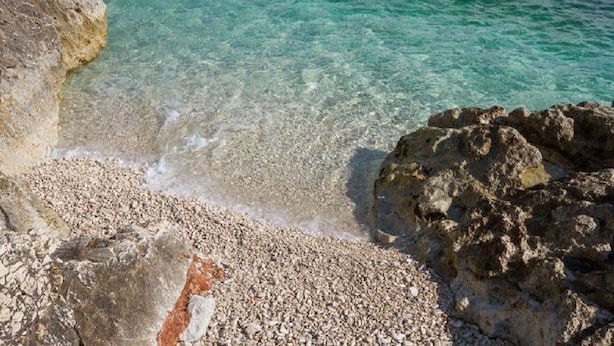 Una costa rocciosa con acque turchesi cristalline.