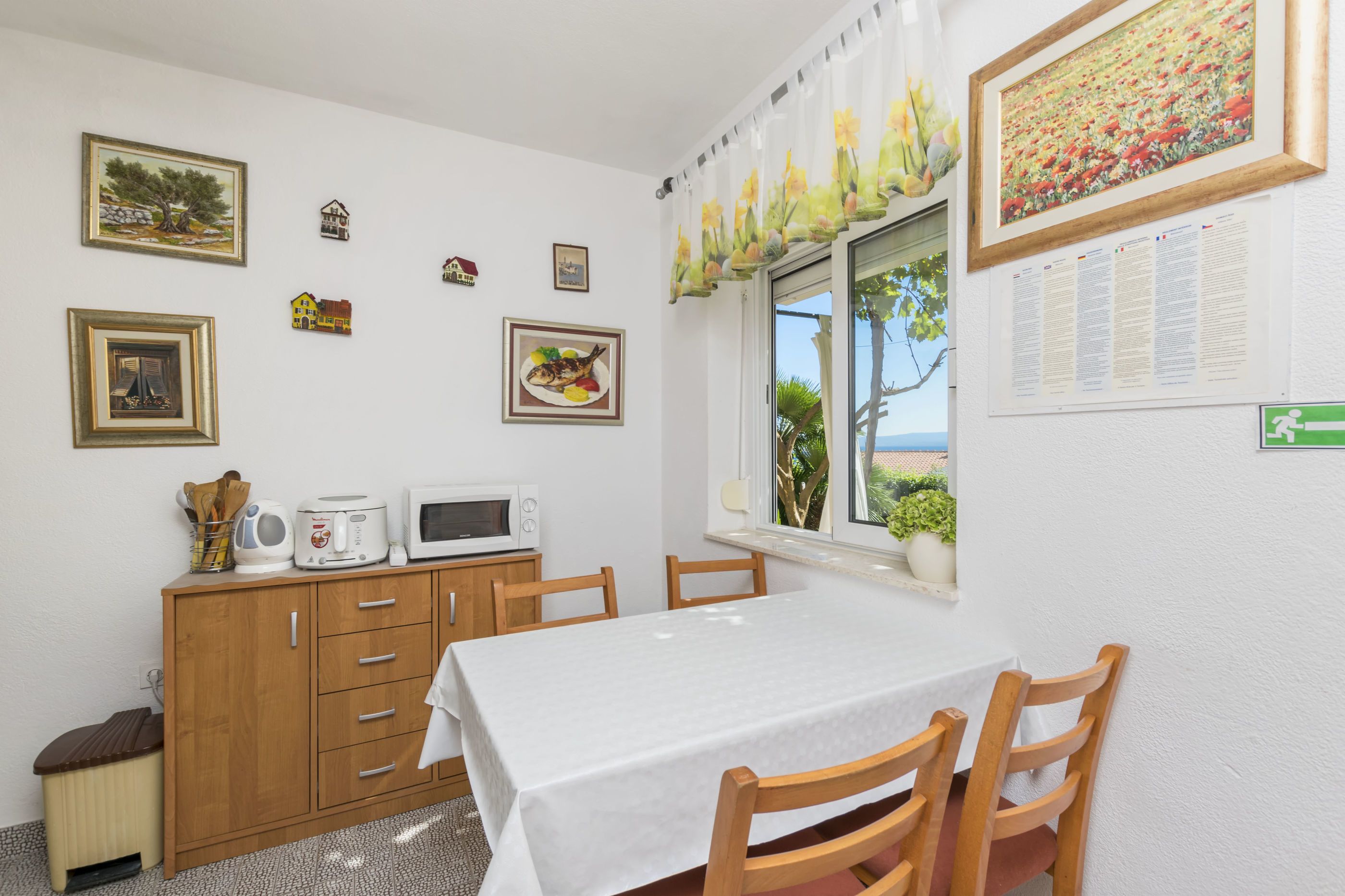 A dining area with a table, chairs, a microwave, and a cabinet.