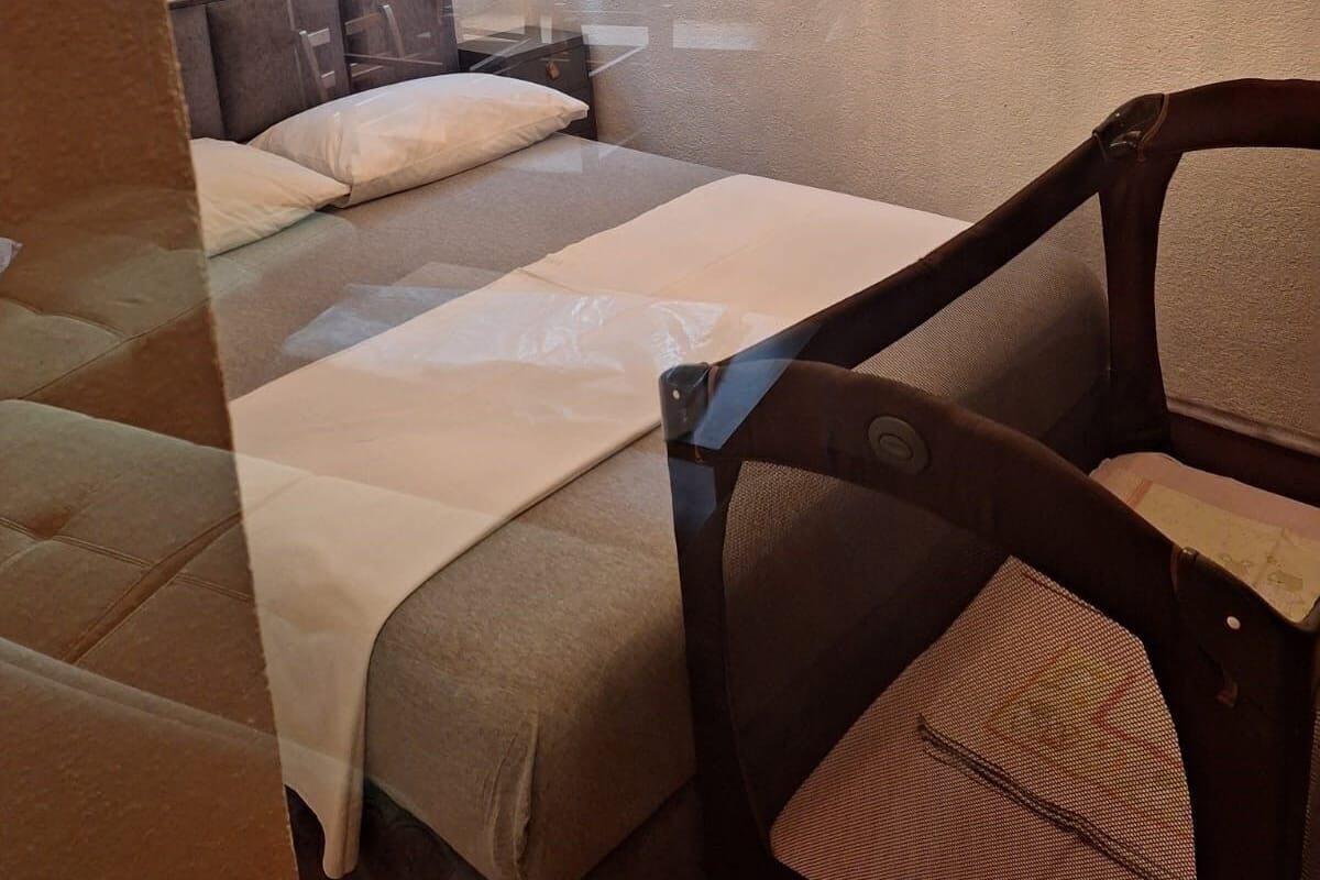 Ein Hotelzimmer mit Bett, Sessel, Nachttisch und einem fenster mit Vorhängen.
