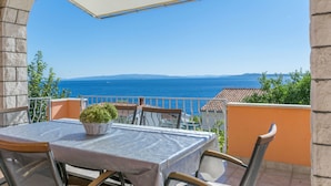 Un balcone con tavolo e sedie, affacciato su una vista costiera.