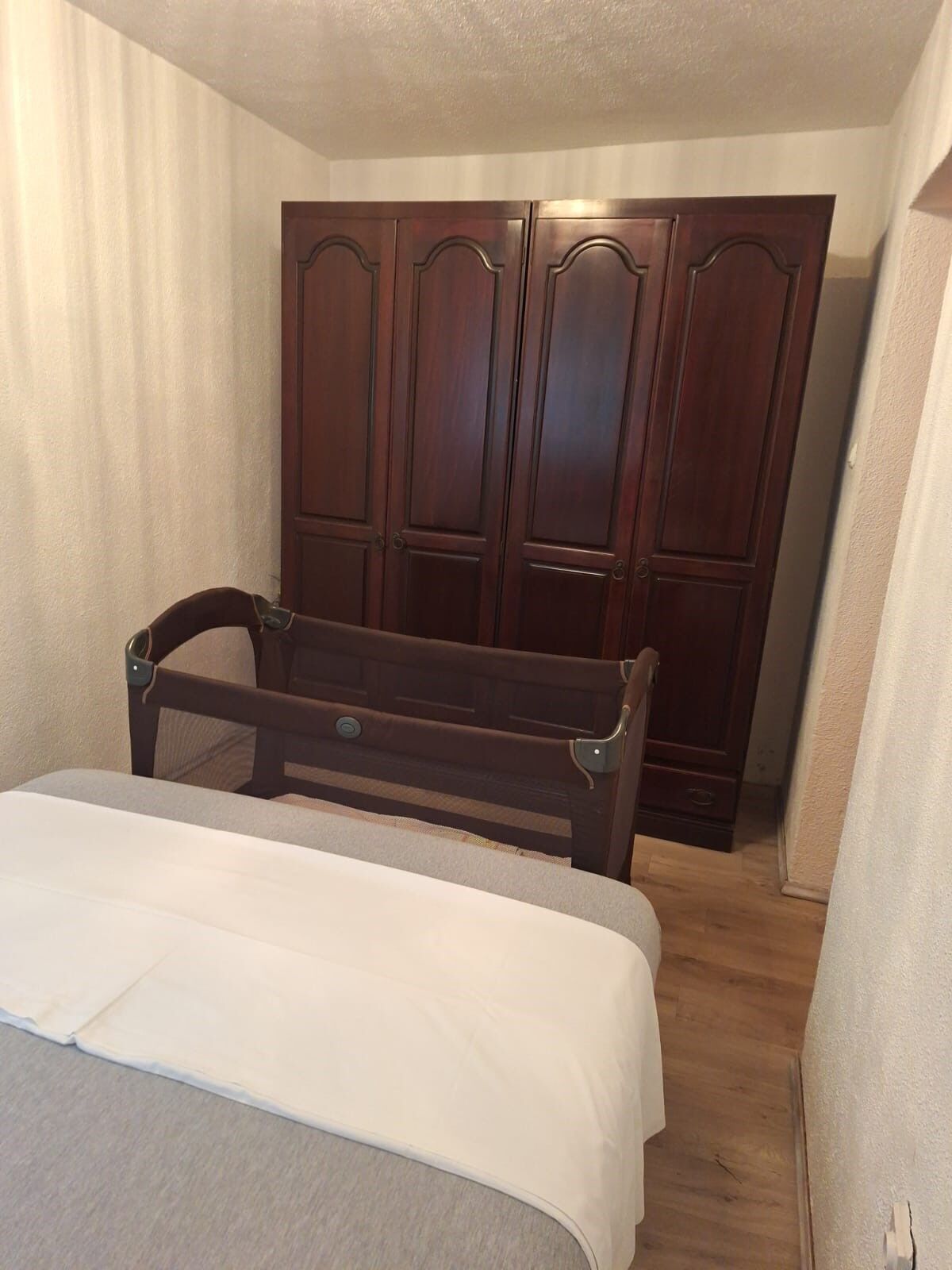 A small, narrow room with a single bed, a wooden chair, and a large wardrobe.