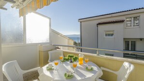 A balcony with a table set for breakfast, including orange juice and a small potted plant. - Apartments Srecko (Duce)