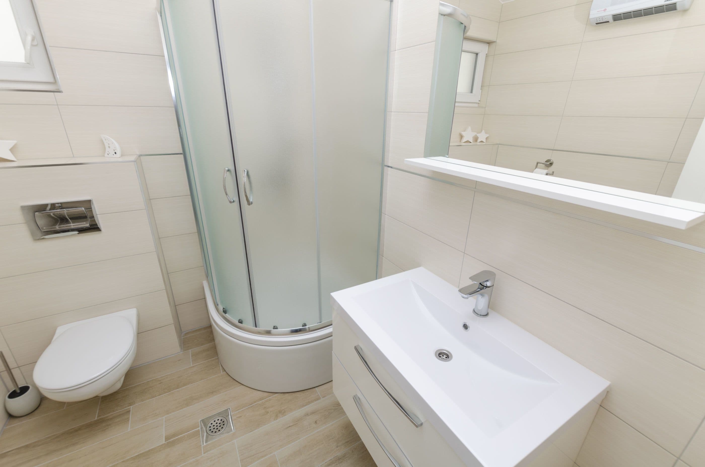 A modern bathroom with a glass-enclosed shower, a white sink, and a toilet.