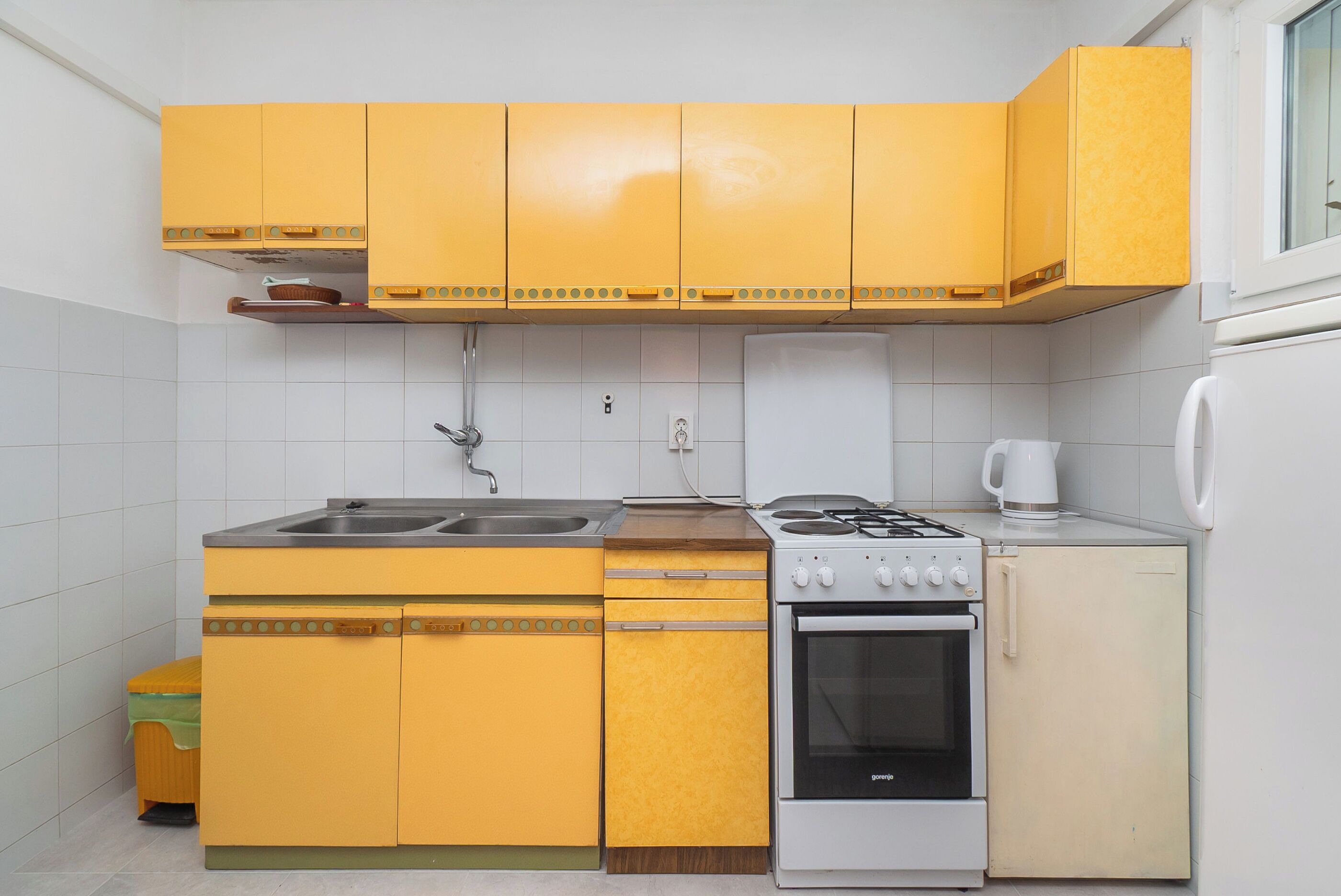 Una cocina compacta con gabinetes amarillos, una estufa, un horno y un refrigerador.