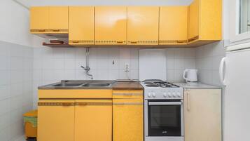 Una cocina compacta con gabinetes amarillos, una estufa, un horno y un refrigerador.