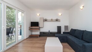 A modern living room with a sectional sofa, a flat-screen TV, and a minimalist design. - Apartment Ljuba (Primosten)