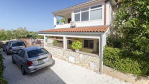 A two-story house with a stone facade, a tiled roof, and a balcony with potted plants. - Apartments Denis (Supetar)