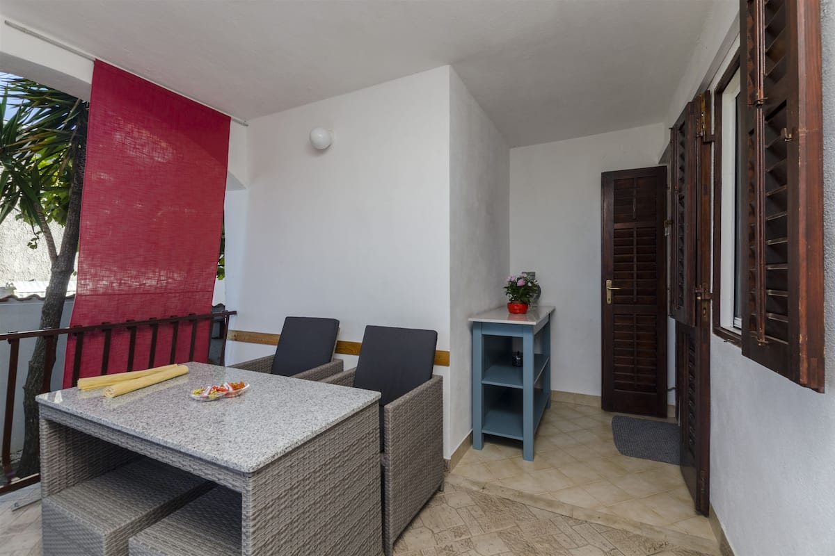 A balcony with a table, chairs, and a red curtain.