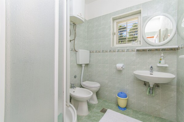 Ein Badezimmer mit Toilette, Bidet, Waschbecken und einem Fenster mit Blick auf Gebäude.