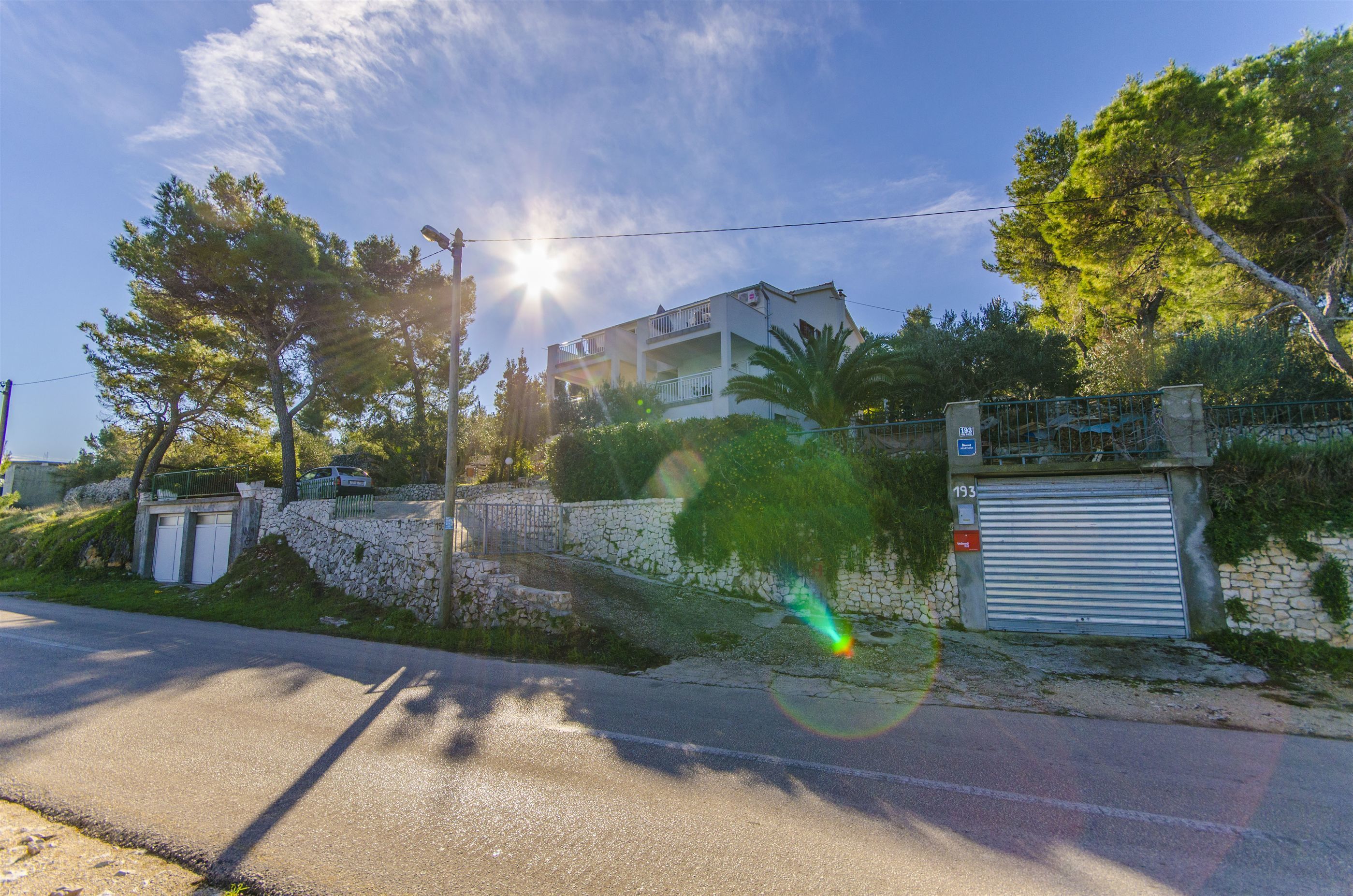 Un immeuble résidentiel avec un mur en pierre, une porte de garage et un ciel dégagé.