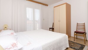 Une chambre à coucher avec un lit, une armoire, une chaise et une fenêtre avec des rideaux.