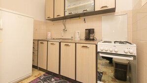 Une cuisine avec des meubles de rangement en bois, un réfrigérateur blanc, une cuisinière et une machine à café.