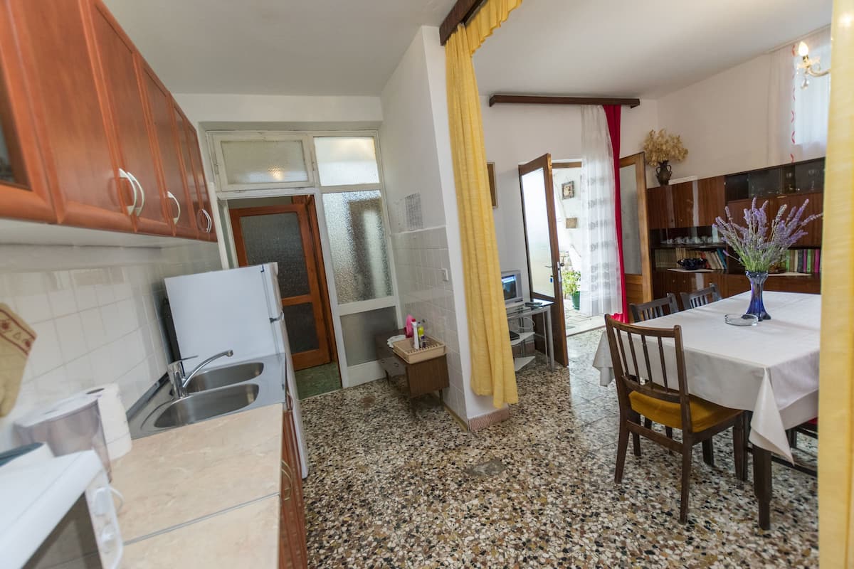 A kitchen with granite countertops, wooden cabinets, a white refrigerator, and a dining area with a table and chairs.