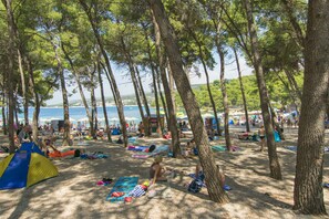 A beach with tents and people relaxing under trees. - Apartment Anka (Primosten)