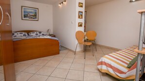 A bedroom with a bed, a chair, a small table, and a bed with a striped blanket. - Apartment Anka (Primosten)