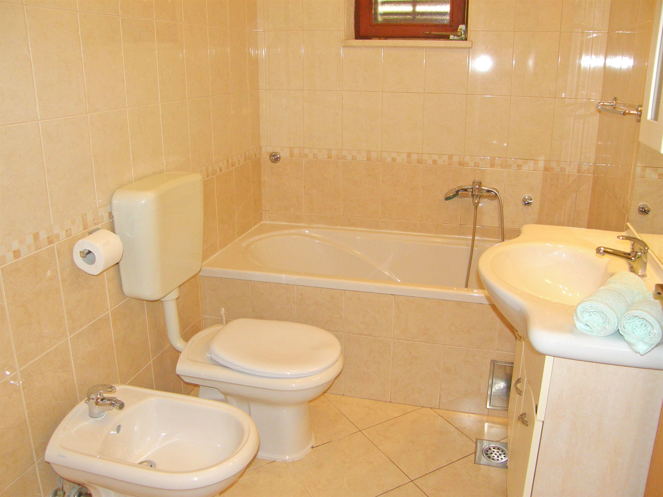 A bathroom with a toilet, bidet, bathtub, and sink.