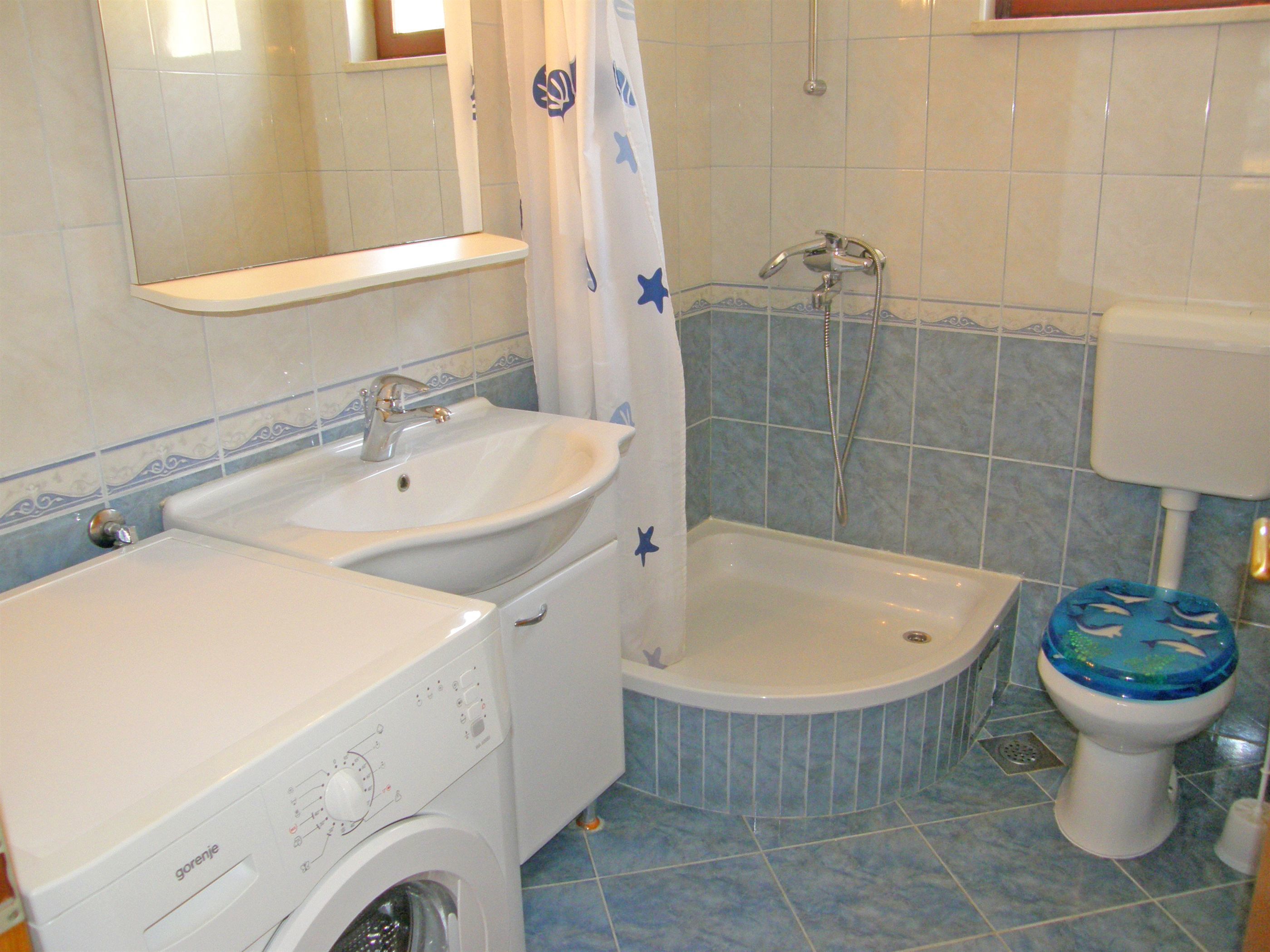 A bathroom with a washing machine, a sink, a bathtub, and a toilet.