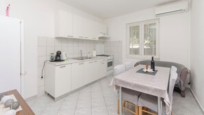 Een kleine keuken met witte kastjes, een gasfornuis en een raam.