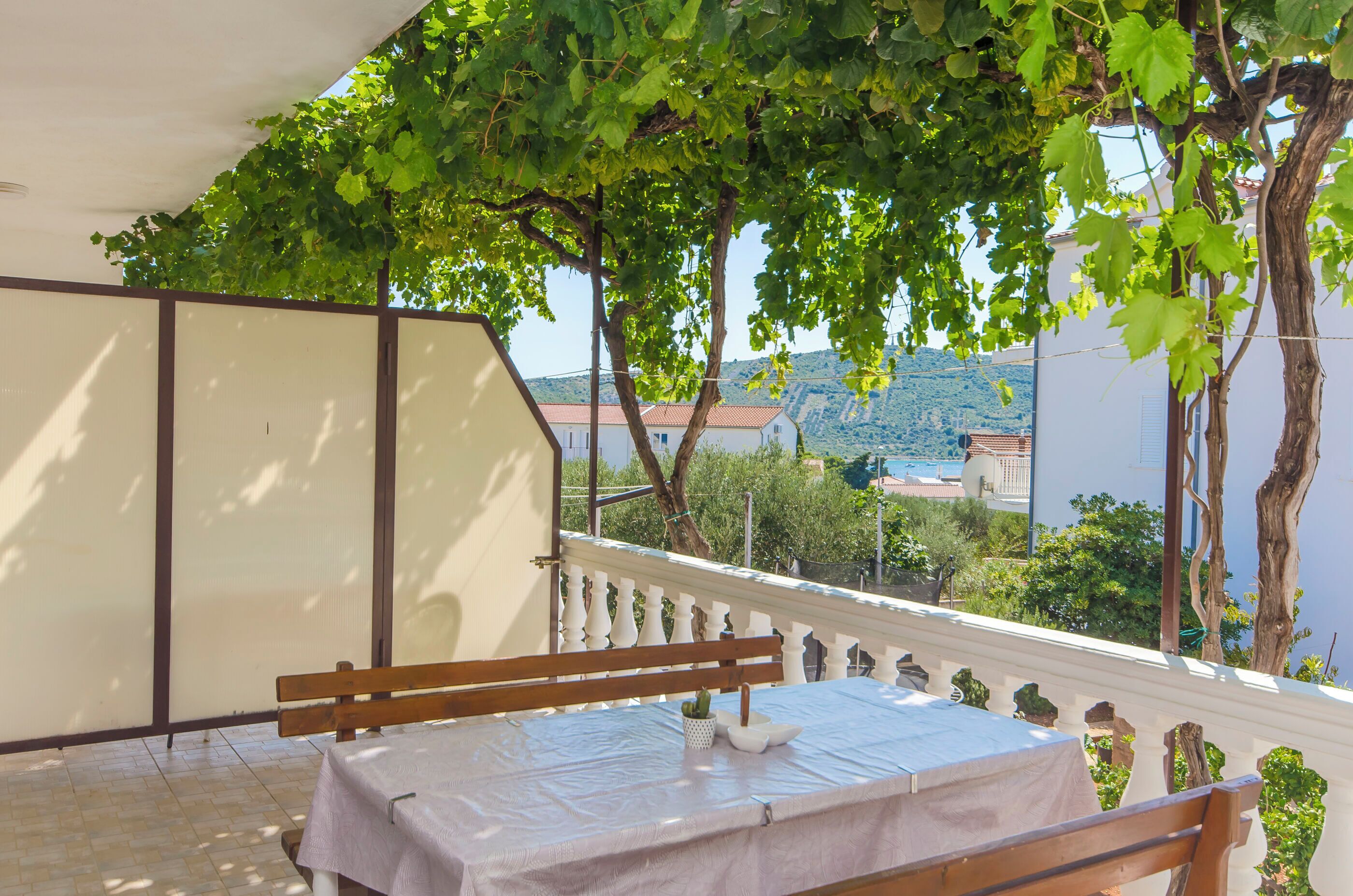 Un balcone con tavolo e panca, affacciato su un paesaggio montuoso.