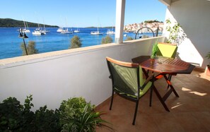 Balcón con mesa y sillas que da a un puerto deportivo con barcos.