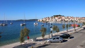 Une ville côtière dotée d’un port de plaisance, de voitures garées et d’une promenade piétonne longeant le bord de l’eau.