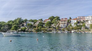 A coastal town with buildings along the waterfront, boats docked, and clear water. - Apartments Katja (Primosten)