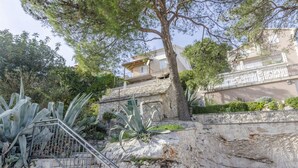 A stone staircase leading up to a building with a balcony, surrounded by cacti and trees. - Apartments Katja (Primosten)