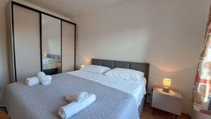 A hotel room with a large bed, a nightstand with a lamp, and a mirror on the wall. - Apartments Karmen A1-A3 (Primosten)
