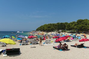Une plage avec de nombreux parasols, des chaises longues et des gens qui profitent de la mer.