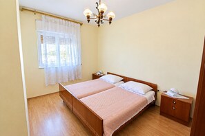 A double bed with a wooden headboard, a nightstand, a bedside table, and a chandelier. - Apartment Lele (Primosten)
