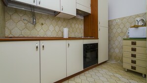 A kitchen with white cabinets, a wooden countertop, a black oven, and a microwave on a wooden cabinet. - House Marija (Arbanija)
