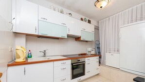 Een moderne keuken met witte kastjes, een ingebouwde oven, een spoelbak en een koffiezetapparaat.