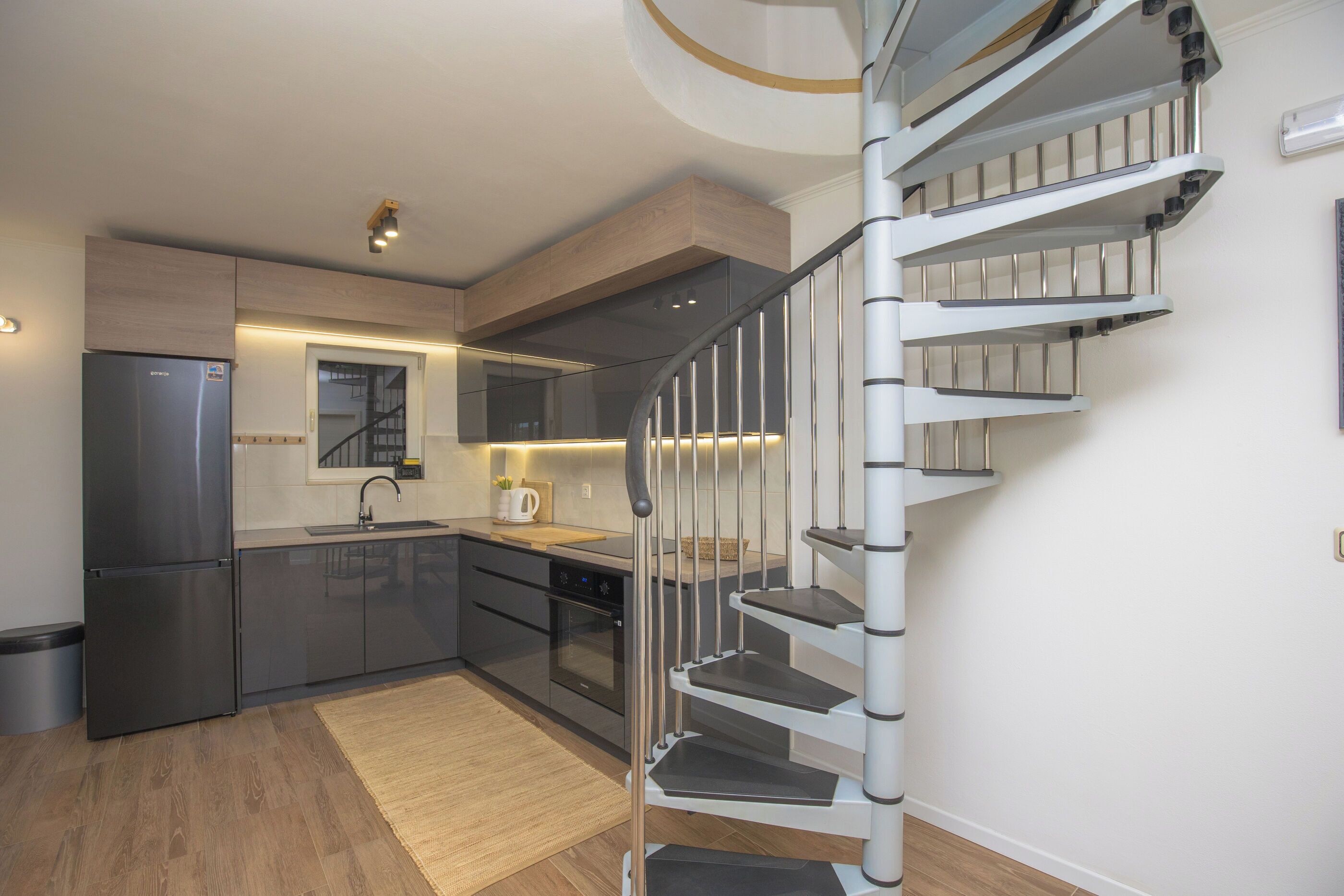 Una cucina moderna con forno integrato, frigorifero in acciaio inox e piano di lavoro in legno.