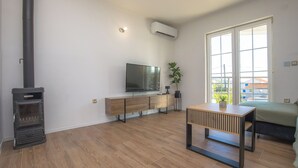 Ein modernes Wohnzimmer mit einer eingebauten Holzofen, einem Flachbildfernseher, einer Holzkabine und einem großen Fenster mit Blick nach draußen.